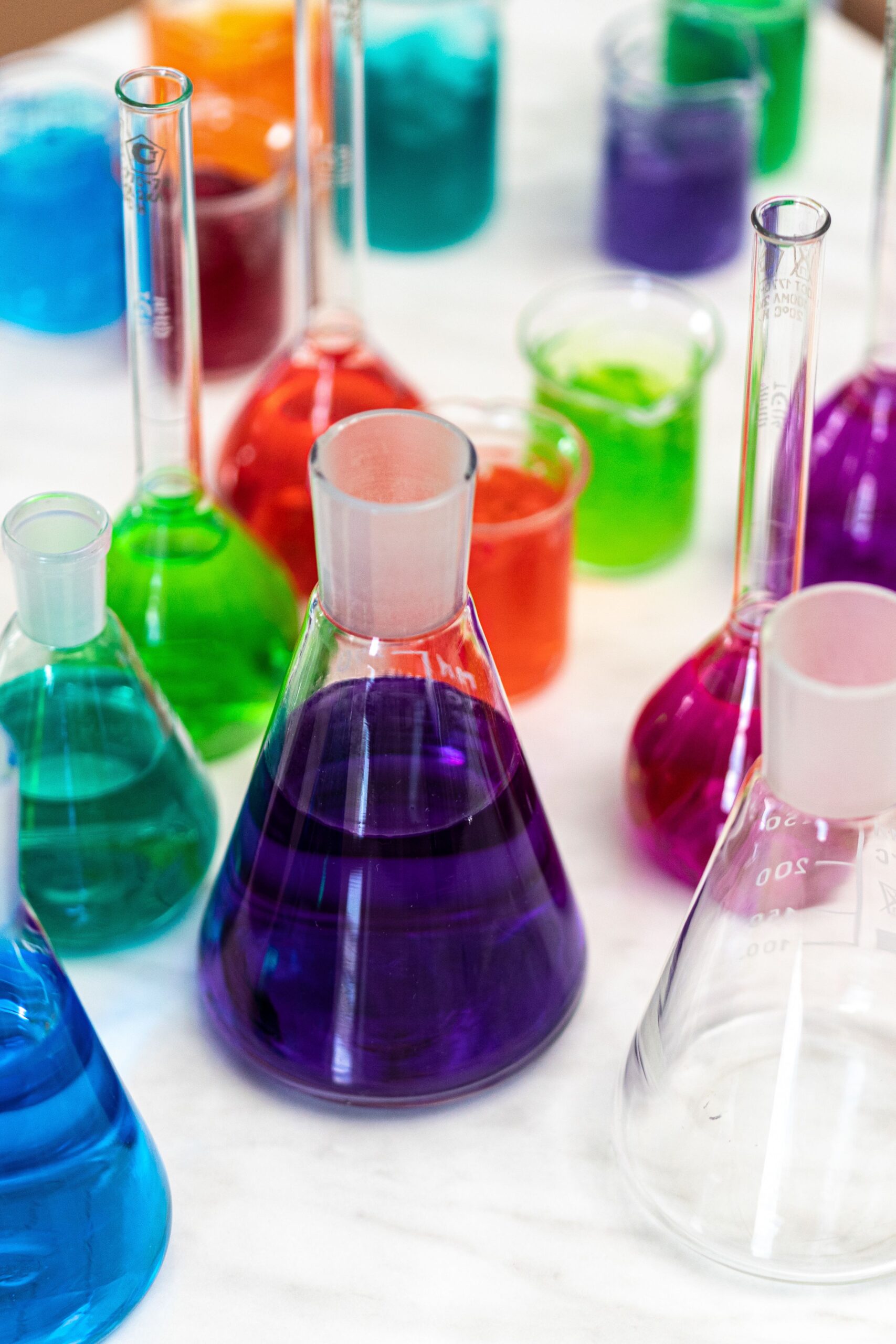 Vibrant chemical solutions in conical flasks in a laboratory setting to illustrate scientific experiments.